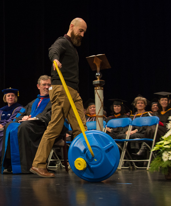 Alumni award-winner Jason C. Gross rolls the Wello WaterWheel onto the stage and encouraged graduates to “share what you know, collaborate and make the world a better place.