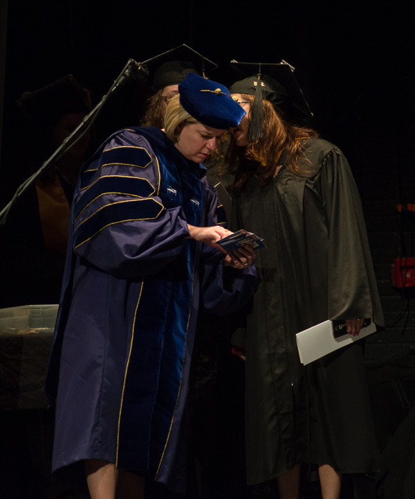 A whisper in the wings: Carolyn R. Strickland, vice president for enrollment management/associate provost, listens to proper pronunciations from graduates. 