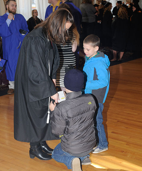 Sheryl E. Snyder, of Montoursville, graduating in applied health studies, gets some help with her gown from sons Chase, 10 (center) and Cole, 7. 