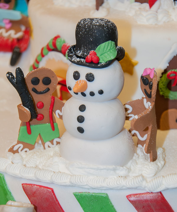 A gingerbread boy and girl assemble a snowman atop Amanda D’Apuzzo’s cake.