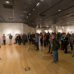 A crowd gathers as the artist speaks.
