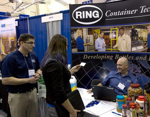 A Penn College student takes a business card from Ring Container Technologies, a Hanover firm on campus to talk with manufacturing engineering technology majors.