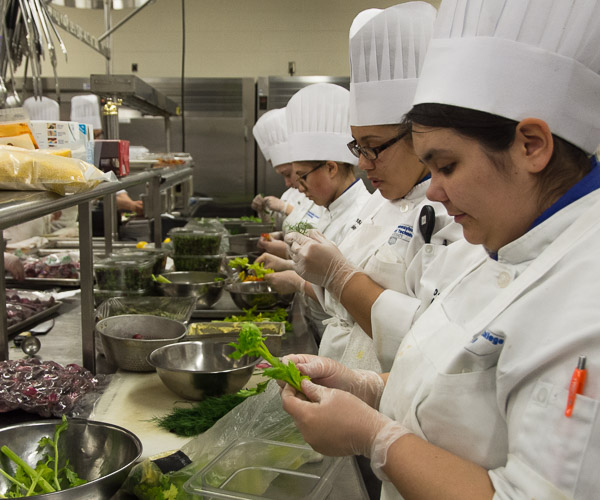 Students prepare vegetables that will later provide color to dinner courses.