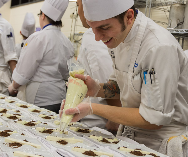 Senior Christopher S. Kasler, of Kendall Park, N.J., adds crème fraiche to the first course.