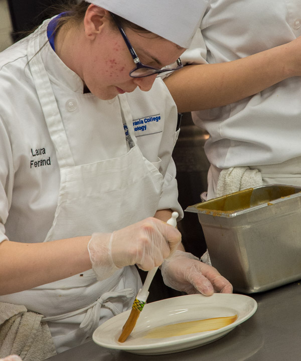 Student Laura M. Ferrand, of Moutainhome, brushes caramel across a plate.