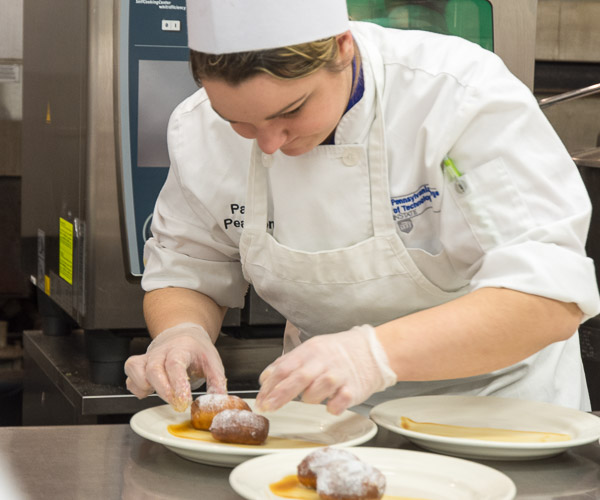 Paige E. Pearson, of Williamsburg, adds beignets to the dessert plate.