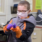 Enamored of the students' clinical garb, Ruhl is permitted to don gloves and a mask.