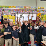 Evergreen seedlings are held aloft by excited schoolchildren in the first-grade class of Barbara Stopper ...