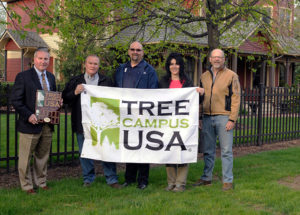 Penn College representatives acknowledge designation as a “Tree Campus USA” outside the green grounds of The Victorian House on main campus. From left are Brett A. Reasner, dean of transportation and natural resources technologies; horticulture instructor Carl J. Bower Jr.; Don J. Luke, director of facilities operations; Andrea L. Mull, horticulturist/grounds and motorpool supervisor; and Andrew Bartholomay, assistant professor of forestry. The plaque will be installed in the Student & Administrative Services Center and the flag will fly outside the Schneebeli Earth Science Center, home to the college’s forest technology and landscape/horticulture majors.