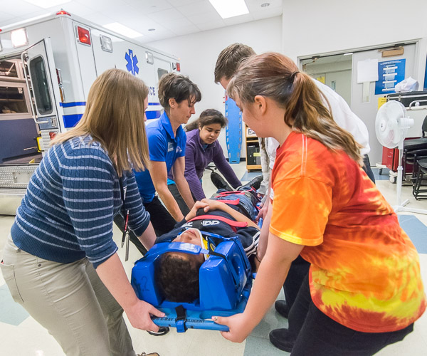 Visitors from Milton Middle School perform a full spinal immobilization under the instruction of Bambi A. Hawkins (in blue), learning laboratory coordinator for the college's paramedic program. The session, 