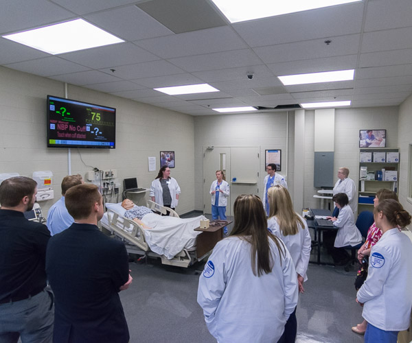 Tina M. Kline (next to manikin), assistant professor of nursing, describes the functions of SimMan 3G.