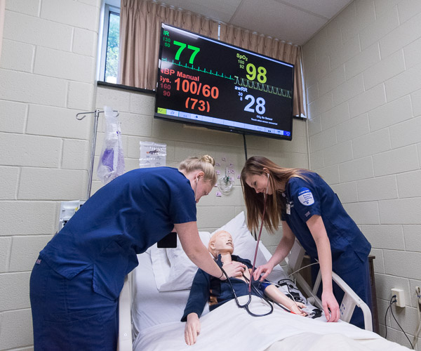 Nursing students check the heart rate of SimJunior, a pediatric patient simulator.