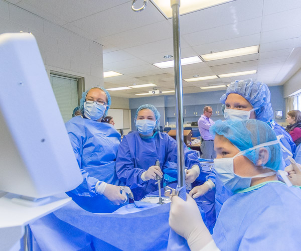 Under the supervision of Scott A. Geist (background), director of surgical technology, students explore the hands-on world of the operating room.