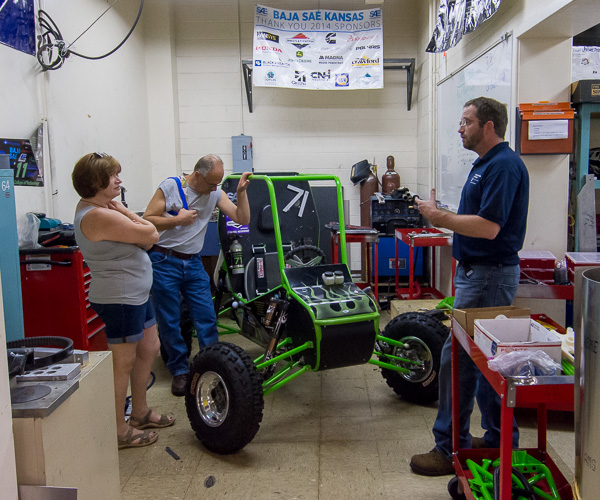 Shaun D. Hack, collision repair and restoration faculty, chats with visitors over the Baja vehicle in the Metal Trades Center. 