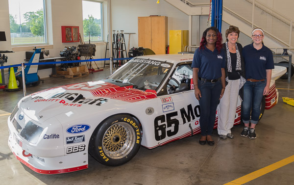 St. James poses by one of her former race cars, flanked by Mathurin (left) and collision repair technology major Genevieve M. Kelly, of Beverly, Mass.