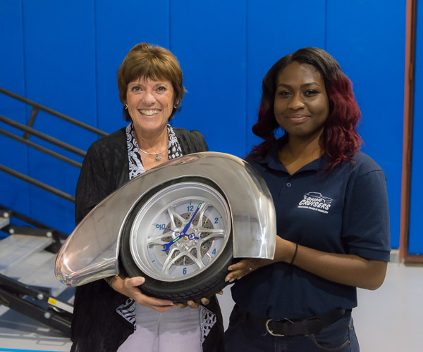 Vanessa Mathurin, of Philadelphia, an applied management major who earned a degree in automotive restoration technology last year, presents keynoter Lyn St. James with a commemorative clock crafted in the restoration lab.