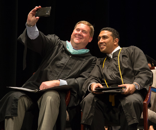 As the college president encourages cellphone photos and social-media sharing, Elliott Strickland, chief student affairs officer, snaps a memory with the student speaker. 