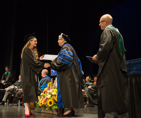 Assisted by Steven P. Johnson, a member of the college's Board of Directors, President Gilmour conveys congratulations to physician assistant graduate Alana S. Androvette.