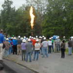 Hard-hatted ETEC visitors watch a live burn from a safe distance ...