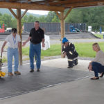 Gary Eide (left), representing the Virginia Bureau of Mines, Minerals and Energy, Division of Gas and Oil, uses a self-propelled welder to heat-seal an absorbent mat. Aiding the demonstration are (from left center) New Pig field operations manager Drew Huff; Moore; and Beth Powell, the company's vice president and general manager.