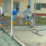 Students and mentor use a variety of tools to spread and smooth the concrete during Wednesday's pour.