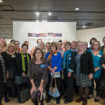 Gallery director Penny G. Lutz (with blue nametag) gathers with some of the artists represented in "Connected by Stitch."