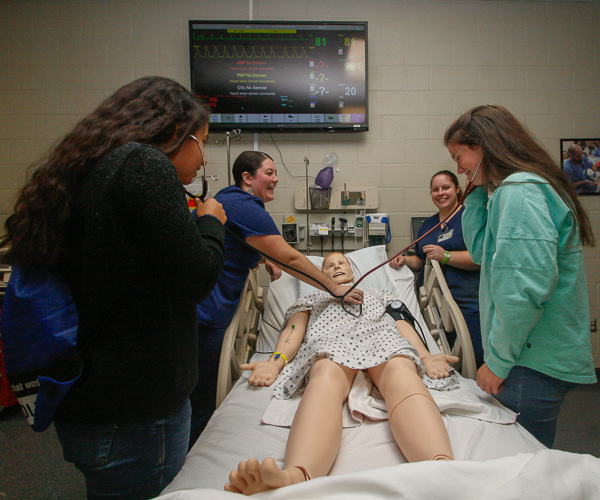 Nursing students Karissa L. Hornberger Pearson (left background) and Kasandra L. Smoyer (right) help visitors listen to the heart and lung sounds of Sim Man 3G. 