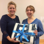 ... is delivered to winner Angela L. Frontz (right) by Sarah S. Moore, one of Schuman's two daughters.
