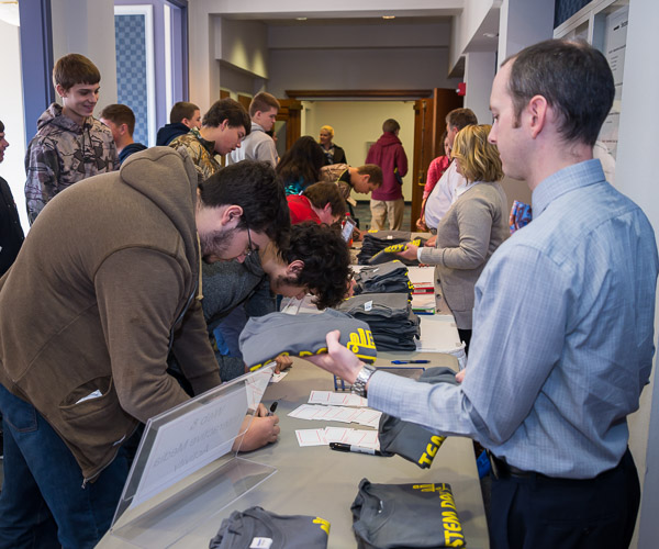 Students representing four area school districts receive nametags and free T-shirts as they are welcomed by staff, including Bradley M. Webb (right), assistant dean of industrial, computing and engineering technologies.