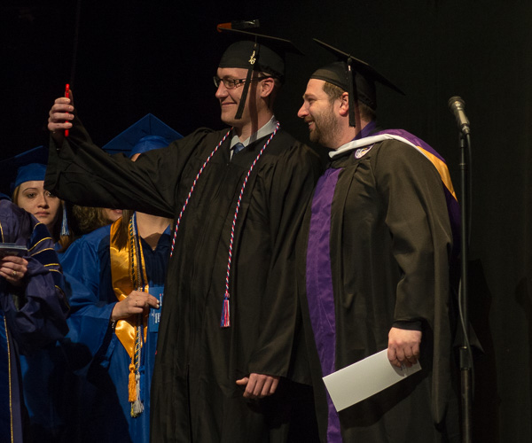 Ryan M. Strickland snaps an on-stage photo with Brian D. Walton, assistant dean of business and hospitality. Strickland, from Fuquay Varina, N.C., earned a bachelor of science degree in technology management. 