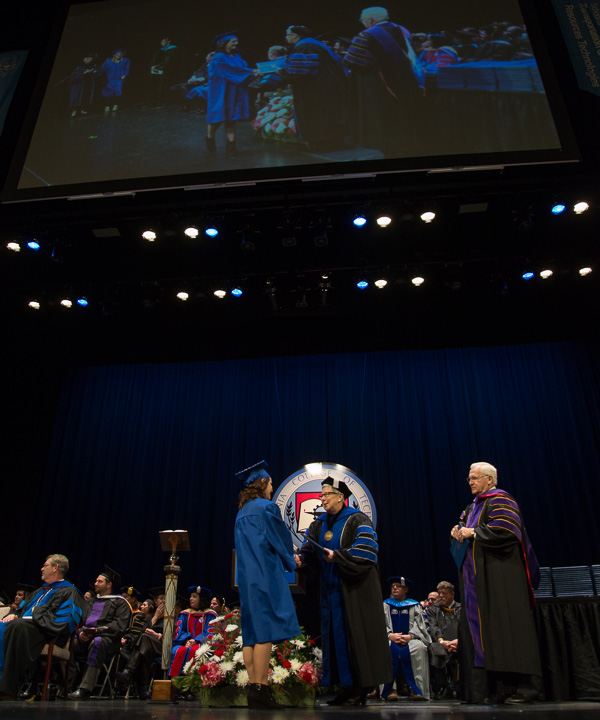 An overhead screen amplifies the grandeur of each graduate's symbolic journey across the stage.