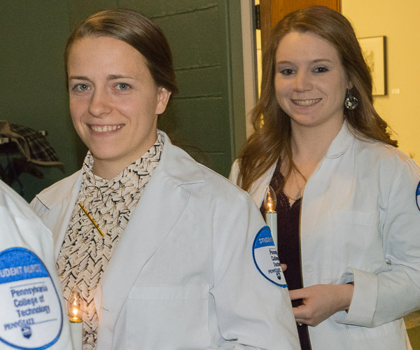 Bachelor-degree nursing students, anticipating Saturday’s commencement ceremony, enter their pinning ceremony in the Klump Academic Center Auditorium bearing candles.