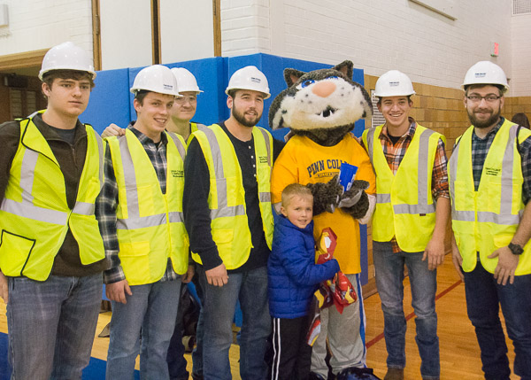 Construction management students don safety vests and share a photo op with friends.