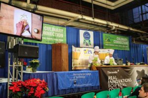 Student Kassandra Sellinger, a culinary arts and systems student from Linden, and Chef Mike Ditchfield perform a cooking demonstration on the Culinary Connection stage at the Pennsylvania Farm Show in January 2016.