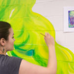 With her own sketch to guide her, Martin adds wisps of color to a previously blank wall.