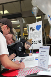 Students sign a large "Thank you" card for Penn College donors.