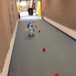 A robot is maneuvered through a cup-lined hallway.