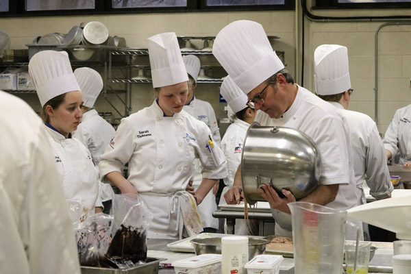 Baking and pastry arts students Katie M. Weakland, of Pennsylvania Furnace, and Sarah I. Tielmann, of Tatamy, observe as Wressell pours a creamy concoction from a mixing bowl.