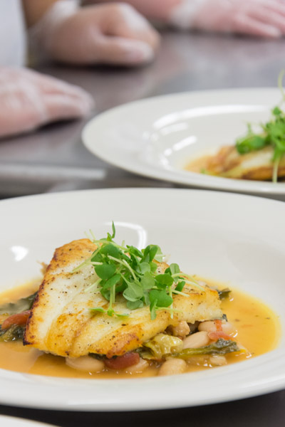 The fish course: “Osteria di Tramonto Halibut,” roasted halibut with escarole, white beans and Italian sausage, shares its name with another of Tramonto’s cookbooks, “Osteria.”