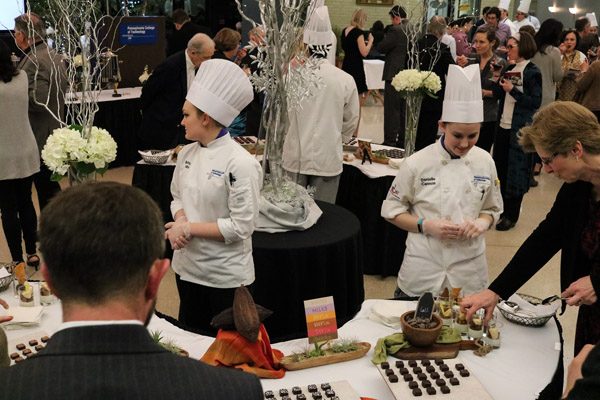 Students Brittany L. Mink, of Allentown, an applied management student who received her degree in baking and pastry arts in 2016, and Danielle L. Cannon, a baking and pastry arts student from Drums, guide the evening’s guests at a table full of Guittard chocolate bonbons.