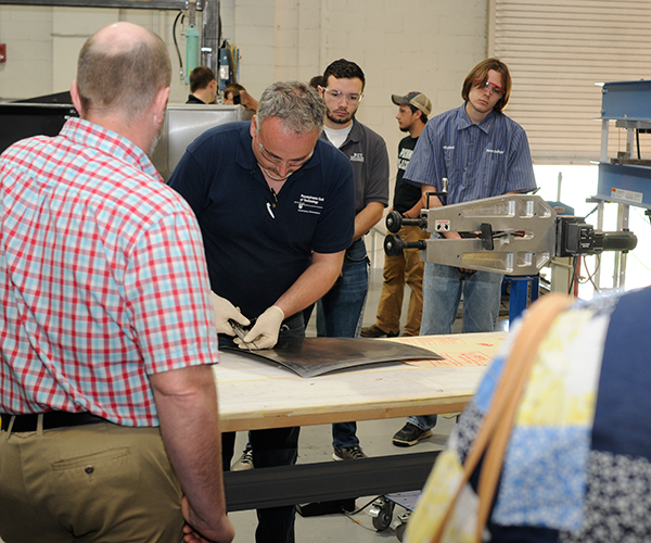 Collision repair instructor Roy H. Klinger provides campus guests with a hands-on demonstration of metalworking.