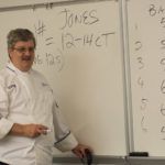 Chef Paul Mach records the mathematical results of students’ bacon-cooking tests.