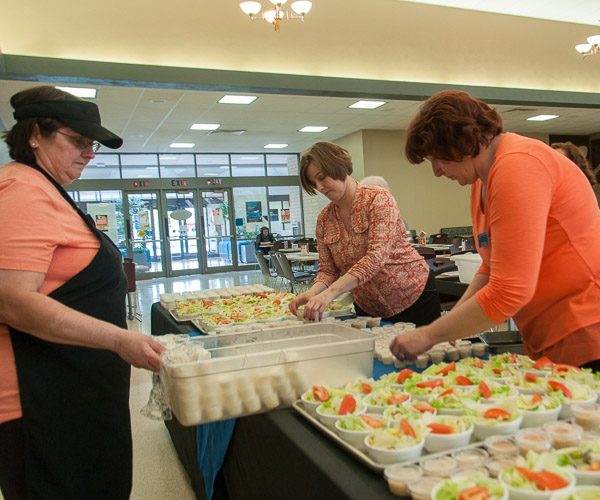 Dining Services employees Barbara E. Easton; Noelle B. Bloom, assistant director; and Vicki K. Killian, manager, prepare a table of salad and dressings for the year-end feast.