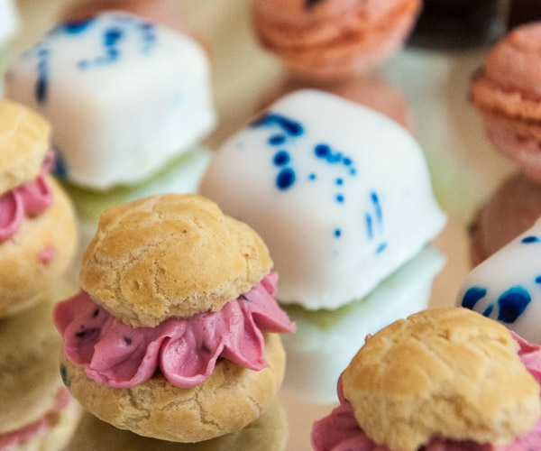 Blackberry cream puffs share a platter with apricot/strawberry petit fours and raspberry macarons in a display by Aucker.