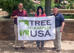 Holding a banner proclaiming Penn College's ongoing “Tree Campus USA” designation are (from left) Don J. Luke, director of facilities operations; Andrea L. Mull, horticulturist/grounds and motorpool supervisor; and Carl J. Bower Jr., assistant professor of horticulture. Not pictured is Andrew Bartholomay, assistant professor of forestry, another collaborator in the college's stewardship success.