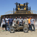 Team members standing in front of a massive Caterpillar D11 bulldozer manufactured nearby are (from left) Mark A. Turek, Travis Scholtz, Darian P. Trego, Shujaa AlQahtani, Trevor M. Clouser, Logan B. Goodhart, Nathan M. Eckstein, Johnathan T. Capps, John D. Kleinfelter, Matthew J. Nyman and Clinton R. Bettner. Not pictured are Michael A. Oldroyd-Costello and faculty adviser John G. Upcraft.