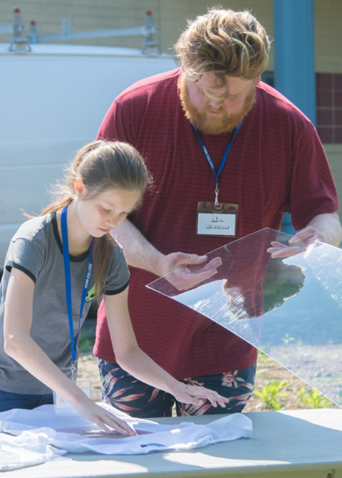 Instructor/local artist Brian J. Spies helps a camper with her sun-printing project ...