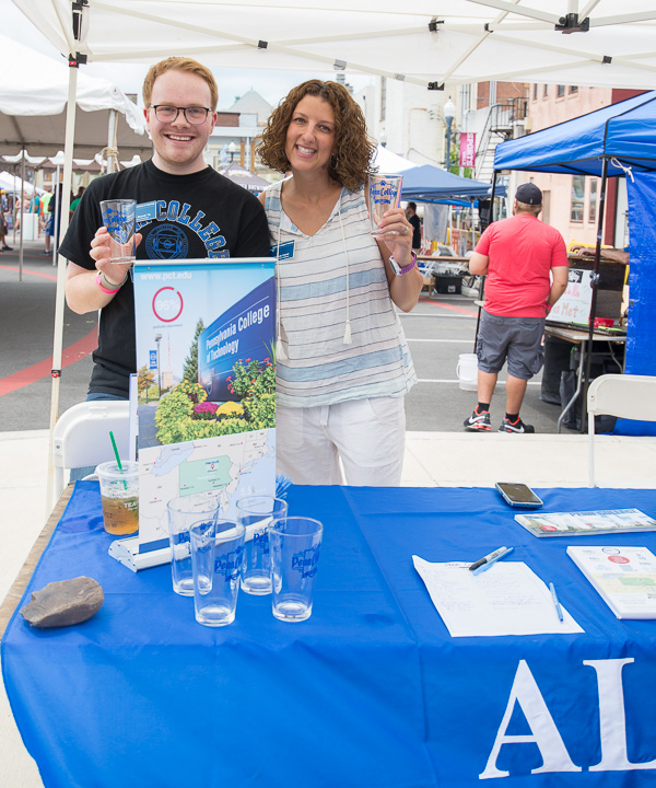 Friendly faces offering Penn College Alumni glasses are: Trevor I. Brandt, admissions counselor, and Kimberly R. Cassel, director of alumni relations. 