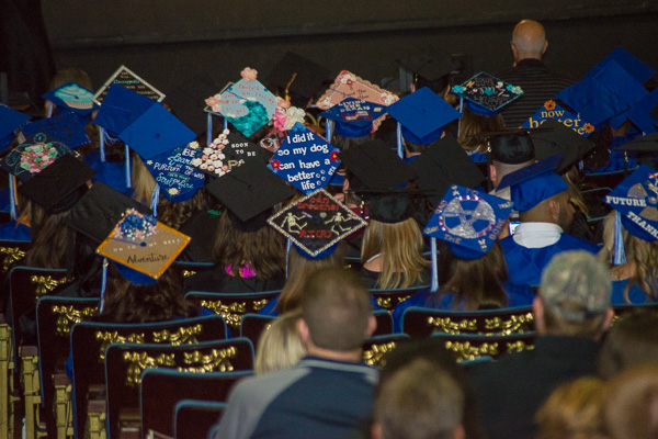 Creatively decorated mortar boards add to the festivity (and humor) of the day – including one at center stating, “I did it so my dog can have a better life.”