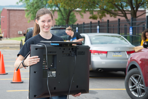 RA Alyssa E. Sickler gingerly carries a TV for an incoming resident.